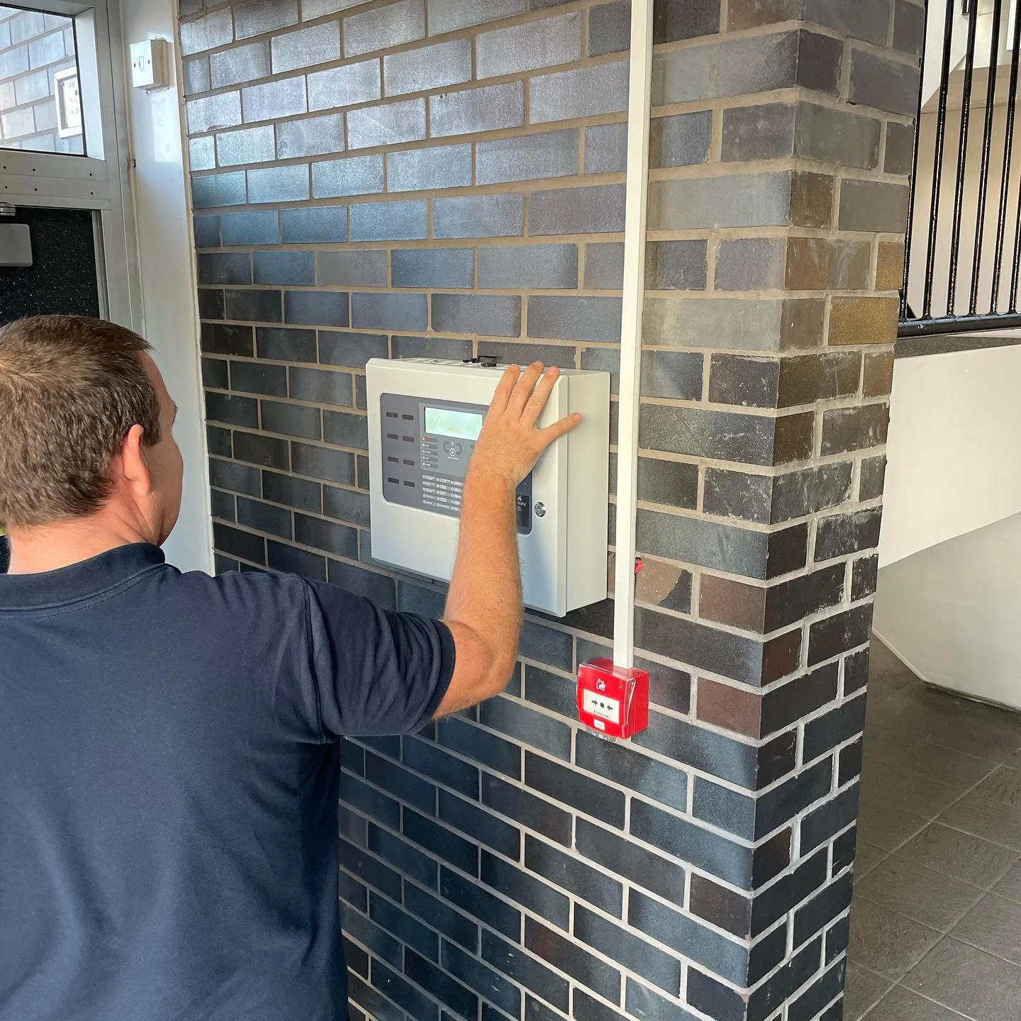 a man is pressing a button on a brick wall